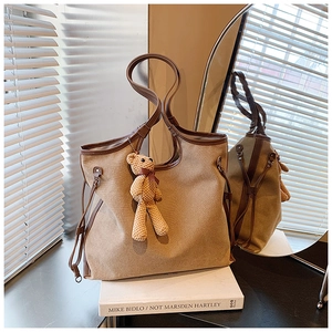 Detail of canvas tote bag with leather trim and a cute knit bear charm accessory