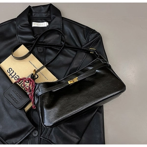 Detail of black baguette bag with gold turn-lock, crocodile texture and mini coin purse