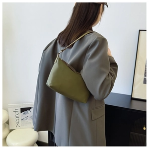 Olive green minimalist crescent shoulder bag worn by model in a modern interior setting