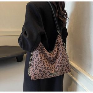 Close-up of leopard print tote bag with black leather strap and gold chain detail