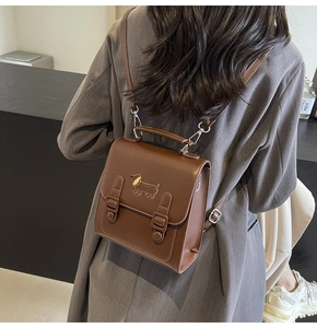 Détail du sac à dos vintage en cuir marron avec logo teckel doré et boucles en métal