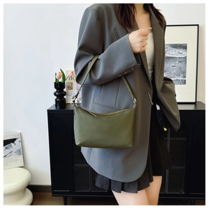 Detail of minimalist olive green nylon crescent bag worn on shoulder in modern setting