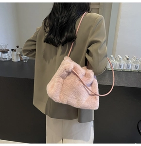 Detail of pink faux fur tote bag with leather strap worn with a dark blazer