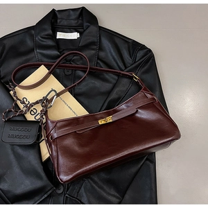 Detail of burgundy baguette bag with metallic rotary clasp and mini decorative pouch