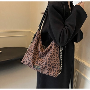Close-up of leopard print tote bag featuring a gold chain detail and premium logo patch