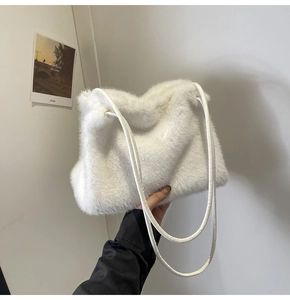 Detailed macro view of white faux fur texture and slim cylindrical straps on the shoulder bag