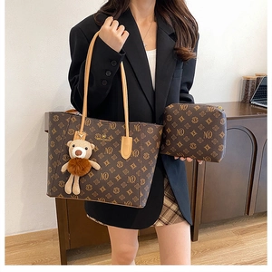 Close-up of vintage MQ monogram tote bag with matching pouch and plush bear charm