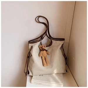 Detail of canvas tote bag with brown trim and cute bear pendant on a book