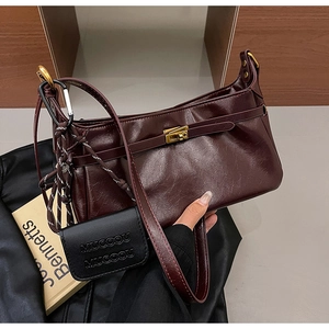 Close-up of wine red faux leather handbag with lychee texture and gold metal turn-lock