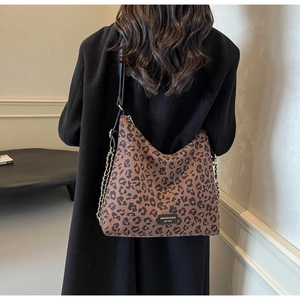 Close-up of leopard print tote bag with gold chain details and black leather straps