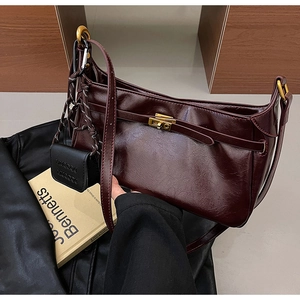 Detail of vintage burgundy oil-waxed leather shoulder bag with gold twist-lock closure
