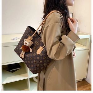Detail of vintage monogram tote bag with bear charm worn with a stylish trench coat