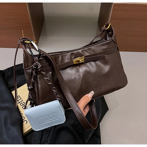 Detail of dark brown vintage leather shoulder bag with gold buckle and mini blue charm