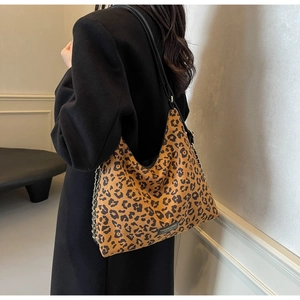 Close-up of leopard print tote bag with black leather strap and metal chain detail