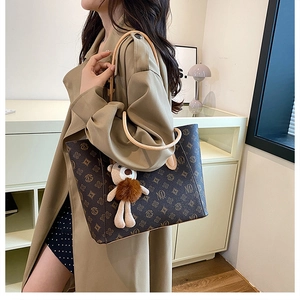 Detail of vintage monogram tote bag with brown bear charm on khaki trench coat