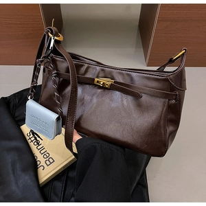 Detail of dark brown vintage shoulder bag with oil-wax texture and mini blue pouch
