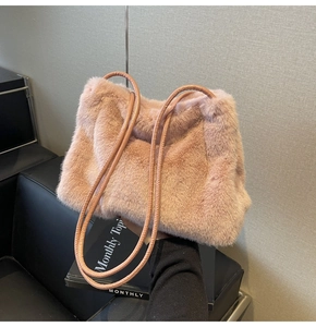 Close-up of pink faux fur shoulder bag texture with slim leather handles in a studio setting