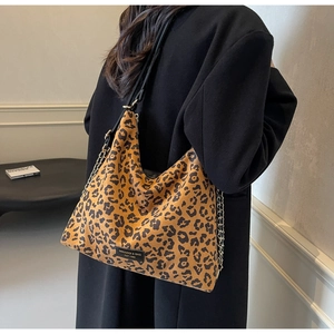 Detail of leopard print tote bag with metal chain strap and brand logo label on canvas