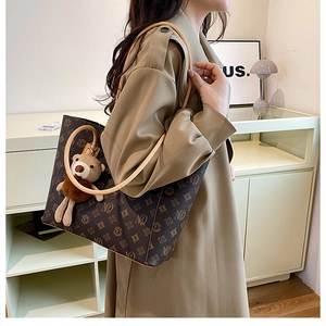 Close-up of vintage brown tote bag with repeating patterns and plush bear charm detail