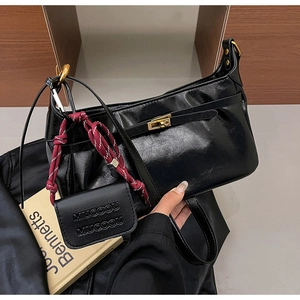 Detail of a vintage black glossy handbag with gold hardware and woven knot charm