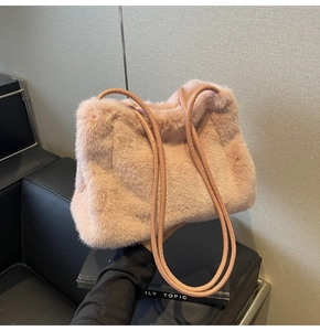 Close-up of soft pink faux fur shoulder bag with slender leather straps and plush texture
