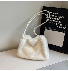 Close-up of plush white faux fur shoulder bag on marble surface with soft texture detail