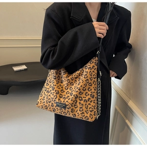 Detail of leopard print hobo bag featuring gold chain strap and brand logo patch