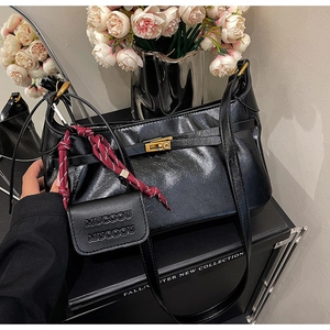 Detail of black glossy leather bag with gold twist lock and woven strap accessory