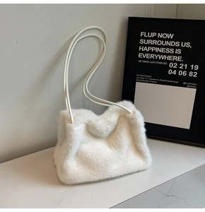 Close-up of white faux fur shoulder bag on marble surface with soft winter textures