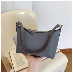 Detail view of the blue-grey leather underarm bag with brown trim and silver buckle