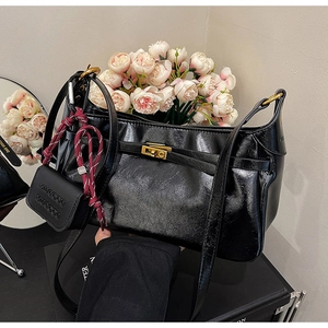 Close-up of black PU leather shoulder bag with gold clasp and red rope charm detail