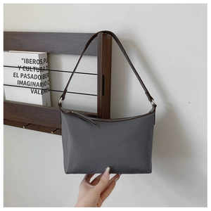 Detail of minimalist gray nylon shoulder bag with brown strap and silver hardware accents