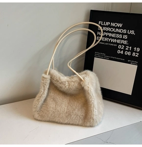 Detail of soft off-white plush shoulder bag with smooth tubular straps on marble surface
