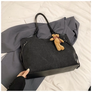 Detail view of large tote bag in black wool blend with leather trim and bear charm