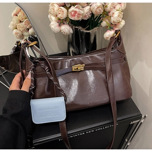Detail of vintage brown leather handbag with gold twist lock and blue brand charm
