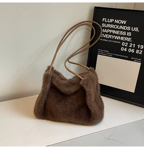 Close-up of brown plush faux fur shoulder bag with leather strap on marble surface