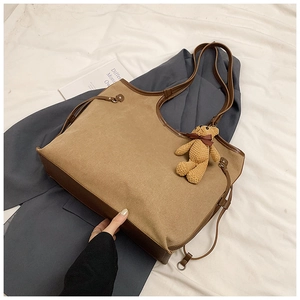 Detail of canvas tote bag with brown faux leather trim and cute teddy bear pendant