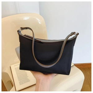 Detail of minimalist black nylon hobo bag with grey-brown faux leather trim and metal ring