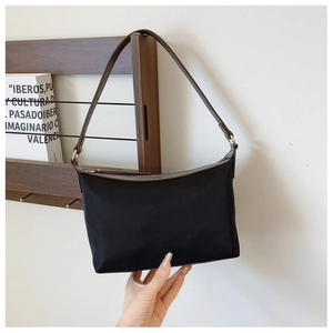 Detail of a black nylon shoulder bag with brown faux leather trim and silver metal zipper