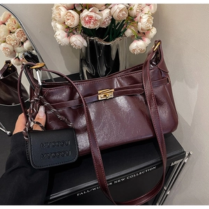 Detail of burgundy glossy leather handbag with gold metal clasp and MUCOOU accessory