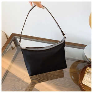 Detail of minimalist black nylon underarm bag with premium brown leather trim and handles