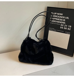 Close-up of soft black faux fur shoulder bag with slender leather straps and plush texture