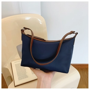Detail of dark blue nylon shoulder bag with brown leather strap and silver metal hardware
