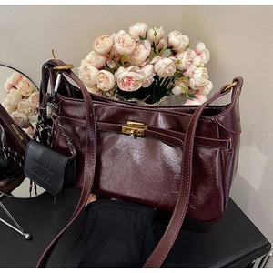 Close-up of wine red vintage handbag with gold clasp and mini charm on black table