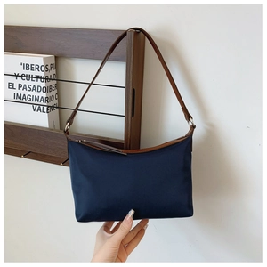Detailed shot of navy nylon hobo bag with brown leather trim and silver zipper hardware