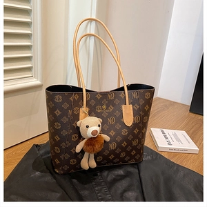 Detail of vintage monogram tote bag with brown leather straps and cute bear charm