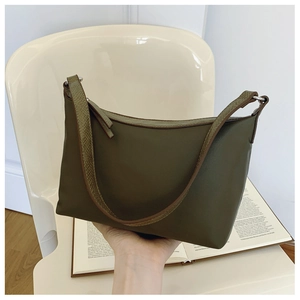 Detail of olive green leather underarm bag with textured strap on a white chair