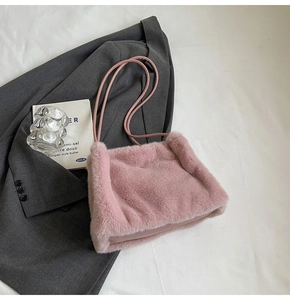 Close-up of pink plush shoulder bag on minimalist white fabric with stylish props