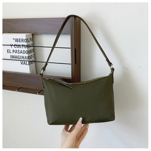 Detailed shot of dark green nylon bag featuring premium brown leather strap and hardware