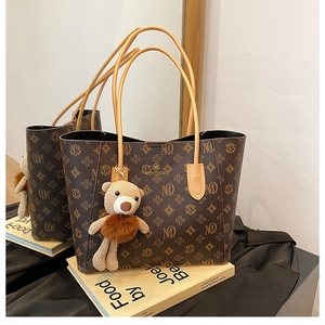 Detailed close-up of dark brown vintage tote bag with pattern and cute bear charm
